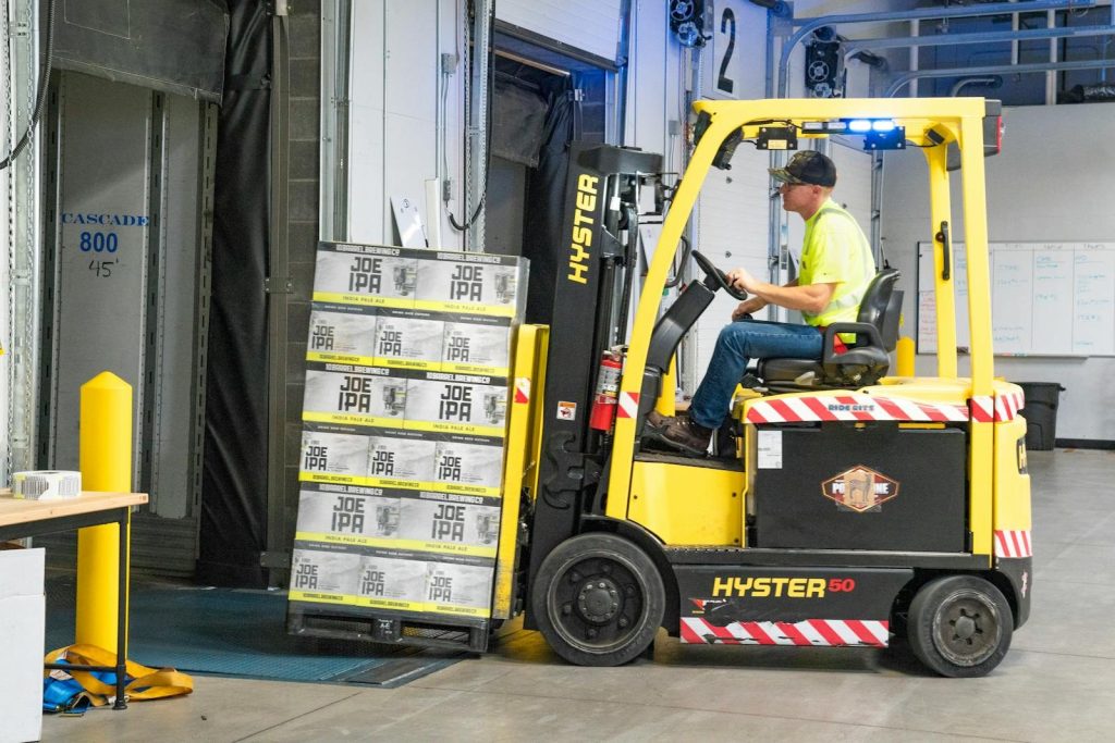 A worker drives a Hyster forklift moving Joe IPA boxes in a warehouse. — Illinois workers compensation attorney Chicago
