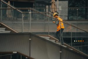 An adult construction worker in a hard hat and vest ascending stairs inside a building. — abogado de compensación laboral en Chicago IL
