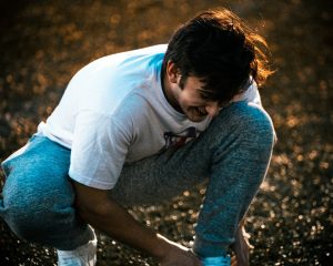 a man kneeling down in the grass with his hands on his knees — Illinois workers compensation attorney Chicago